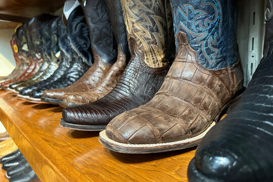 Closeup of row of cowboy boots western clothing retro stylish leather shoes.