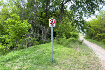 Naklejka premium No fire sign in green garden or park, warning about danger, information about fire prohibition, attention, no fire inscription on whiteboard in forest.