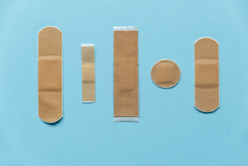 Different kind of shape and size of adhesive bandage elastic medical plasters isolated on blue background.