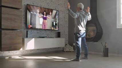 mature person exercise at home watching online workout on television,middle age male training remote with personal trainer livestreaming on tv