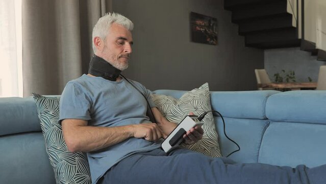 mature man with neck pain using magnetotherapy at home
