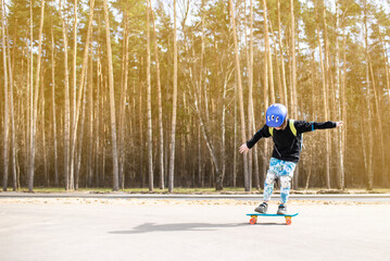 happy child schoolboy with a backpack goes to school on a skateboard. a joyful boy with protection...