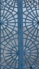 Blue painted traditional patterned iron garden door of an old house. Blu colored iron railings