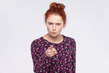 Portrait of serious bossy young adult redhead woman wearing dress pointing finger at camera...