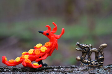 The phoenix bird made of plasticine and the dragon figurine is a fictional fairy-tale character.