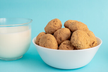 Oatmeal cookies on a white plate, white milk in a transparent glass side view on a blue background. High-quality photo