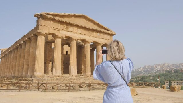 female taking photos of valle dei templi using smartphone agrigento italy,tourist photographs valley of the temple