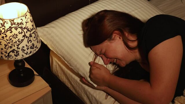 Unhappy woman lie in bed and hysterically cry into pillow in dark bedroom. Splash out emotions, sob uncontrollably. Emotional breakdown, stress, sufferings. Depression, night hysterics before sleep.
