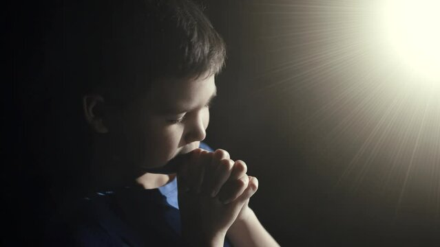 Light shines on the praying boy