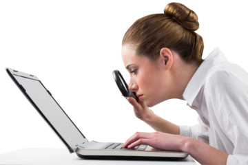 Businesswoman typing and looking through magnifying glass