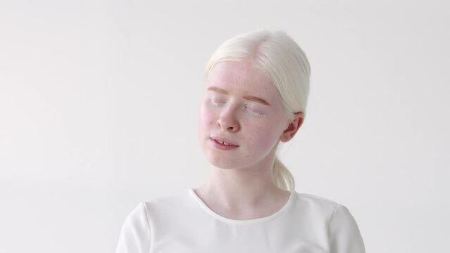 Beautiful albino teen girl, cute pretty model wearing white t-shirt standing on white studio background. Inclusive unusual natural beauty, inclusion, albinism and diversity concept.