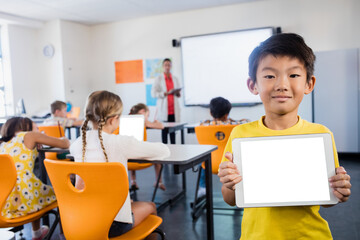 Young boy holding digital tablet while standing