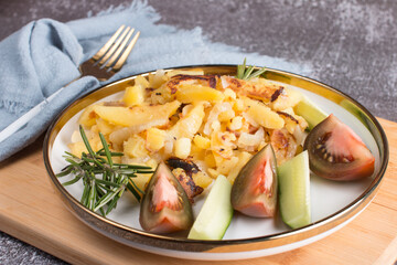 homemade fried potatoes with vegetables. Cucumber and tomato on a white plate with a table napkin