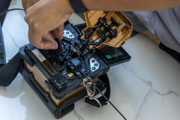 Optical fiber installation with Digital Fiber Optical Fusion Splicing machine. High precision fiber optic cleaver is being used during a fiber optic wire install at House.  Welding of optical fibers.