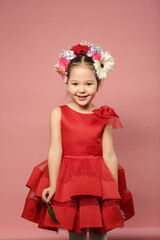 little girl in red dress with flowers in hair dress happy close up portrait on pink background