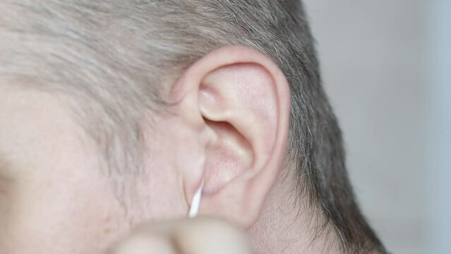 man cleaning his ears with a cotton swab