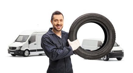 Auto mechanic holding a tire in front of two white vans