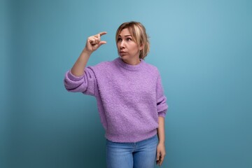 attractive blond young millennial woman in a casual look measures her hands on a bright background with copy space