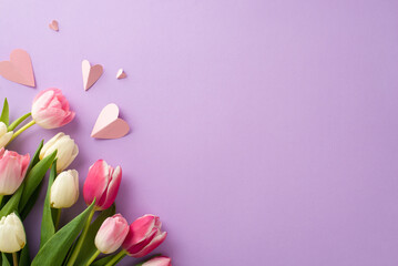 Mother's Day floral gift concept. Top view flat lay of pretty tulip flowers, paper hearts on a soft pastel violet background with space for text or advert