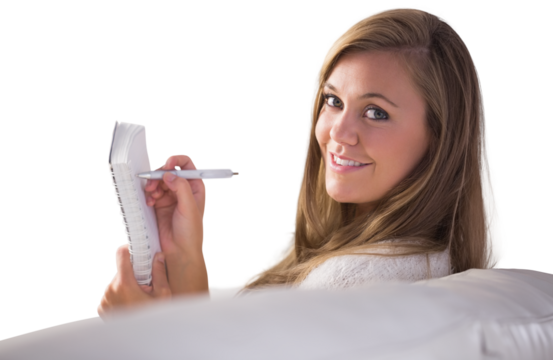 Pretty blonde relaxing on the couch writing in notepad