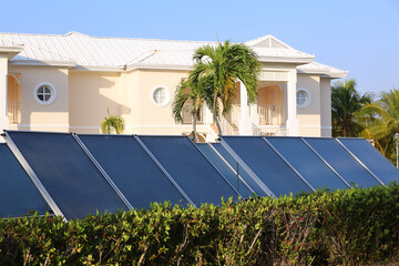 Solar panels on background of villa and palm trees. Clean ecological electric energy
