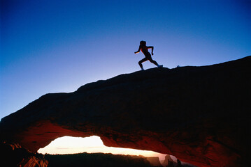 Silhouette of Woman Running on Rock Formation