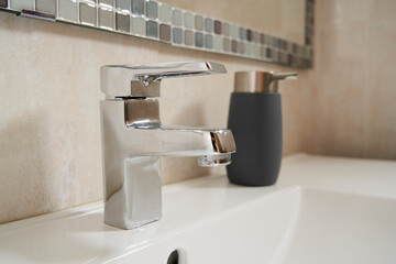 Close-up of a silver bathroom faucet and soap dispenser