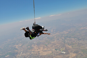 Skydiving. Tandem is falling above the summer land.