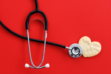 Heart health concept - stethoscope heart-shaped cookie on red suffer cardiac arrest or heart attack