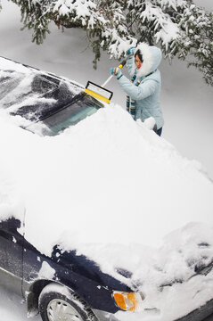 Woman Brushing Snow off Van