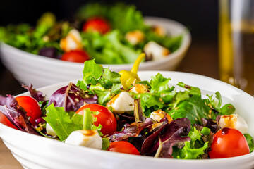 Salad greens in a bowl with cherry tomatoes and balsamic vinegrette.