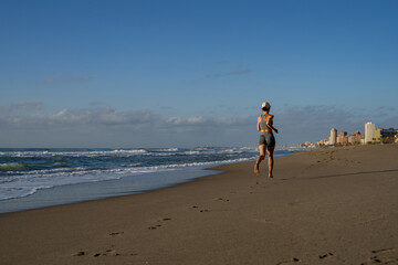 beautiful young girl is engaged in jogging on the seashore rear view