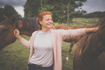 Pretty, young, redhead woman with her lovely horse, during her favorite leisure
