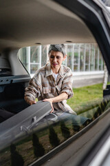 one senior woman pack luggage baggage suitcase in the trunk of the car