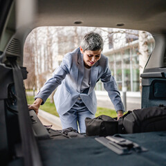 Fototapeta na wymiar one senior woman pack luggage baggage suitcase in the trunk of the car