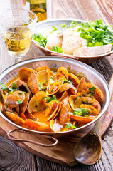 Traditional Portuguese seafood cataplana with vongole clam in white wine sauce served as close-up in a rustic  design cataplana pot