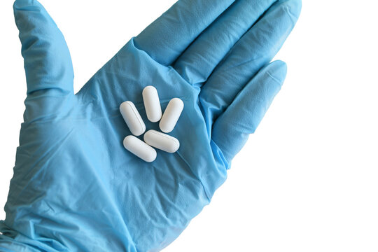 White Tablets Pills In Hand Wearing Blue Surgical Gloves. 