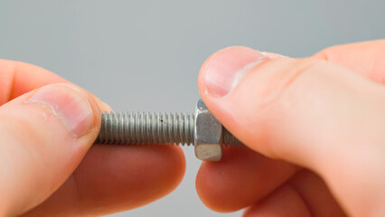 Men hands tighten nut on the screw closeup