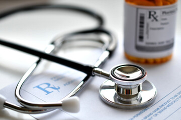 A doctor's stethoscope on a prescription RX pad with a bottle of medicine