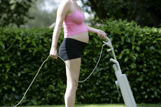 Pregnant Woman Mowing Lawn with Vacuum Cleaner