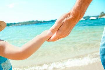 Fototapeta na wymiar A Hands of a happy parent and child in nature by the sea on a journey background