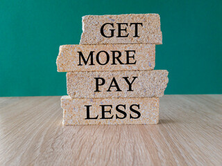 Get more pay less symbol. Concept words Get more pay less on brick blocks on a beautiful wooden...