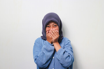 Young Asian girl in hijab laughing and embarrassed giggle covering mouth with hands