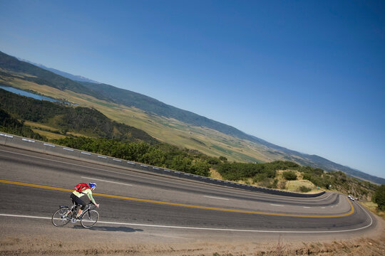 Woman Riding Her Bicycle Down a Hill Toward Steamboat Springs, Routt County, Colorado, USA