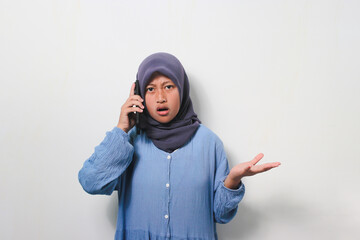 Young Asian girl in hijab looks shocked while using mobile phone