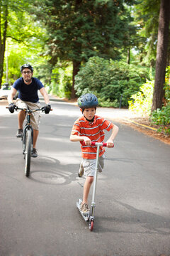 Boy Riding Scooter with Father following on Bicycle, Washington Park, Portland, Oregon, USA