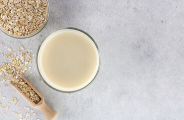 A glass of oat milk and oatmeal on gray background. Top view. The concept of alternative lactose-free dairy products.