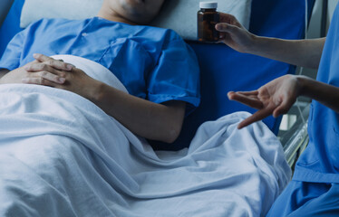 Side view of diverse doctors examining Asian female patient in bed in ward at hospital.