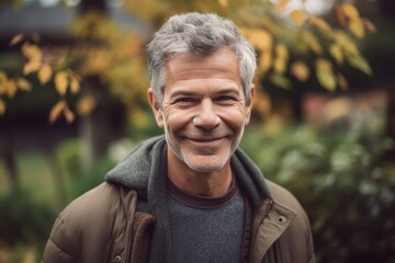 Portrait of handsome mature man with grey hair in autumn park.