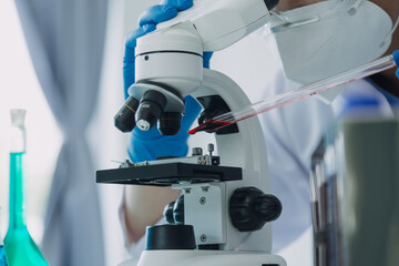 biochemical research scientist team working with microscope for coronavirus vaccine development in pharmaceutical research labolatory, selective focus